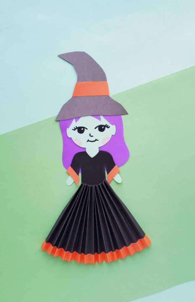 Halloween witch craft for kids made with paper featuring an accordion skirt