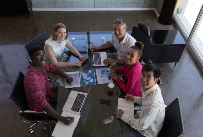 A group of people sitting around a table with laptops.