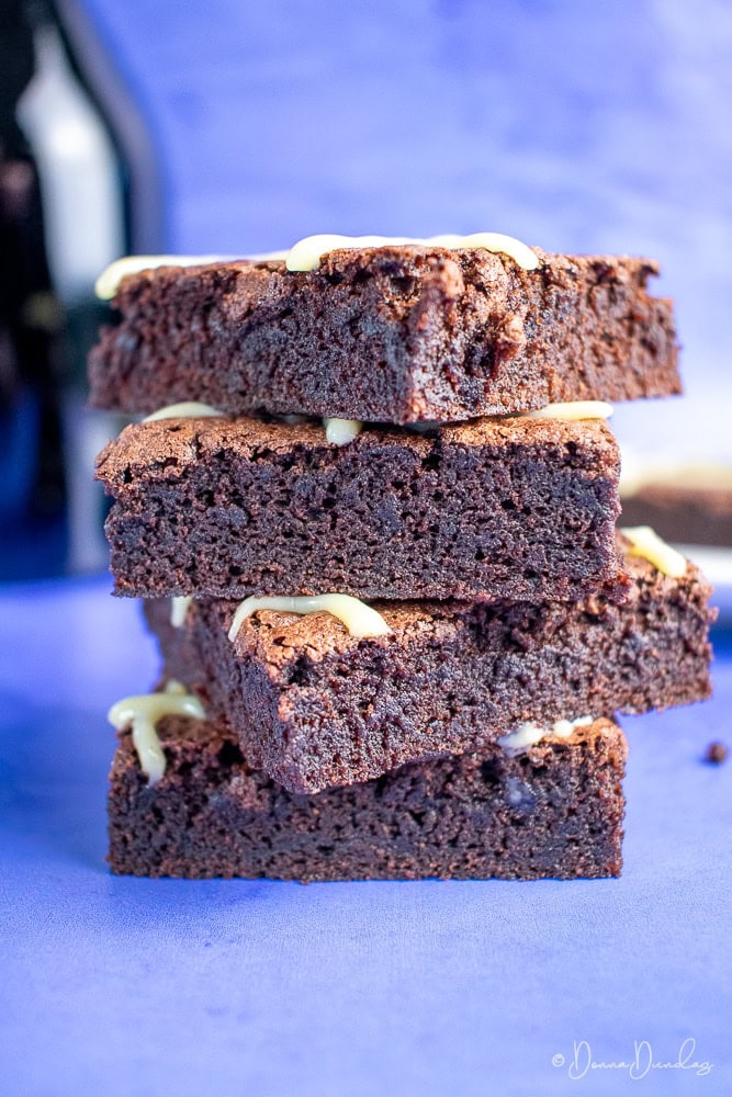 Stack of Bailey's Brownies on blue background, with bottle blurred in the background