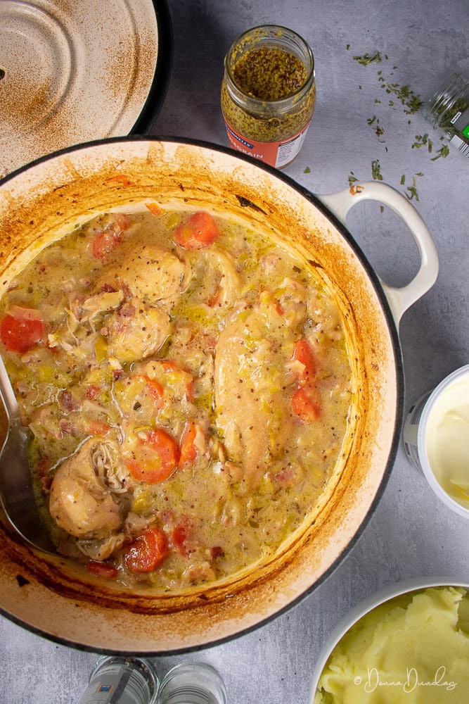 Cider and Chicken casserole in cast iron cooking dish, mustard, tarragon, mash surrounding