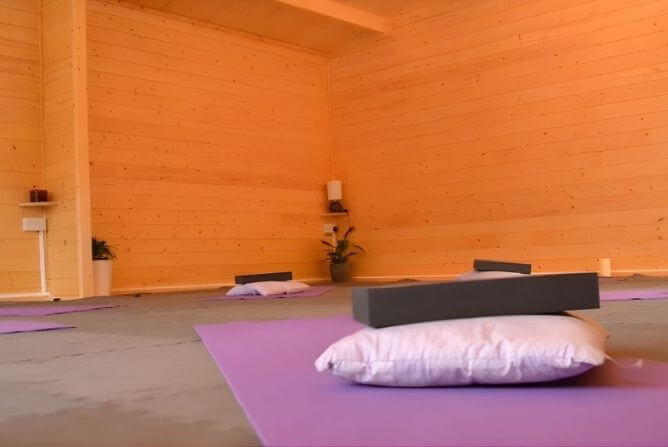 Woman practising a gentle child’s pose stretch on a yoga mat in a wooden studio in Croxley Green.