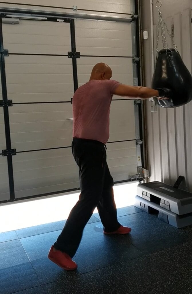 Man traint zelfstandig op een boksbal in de gym, gefocust op techniek en kracht.