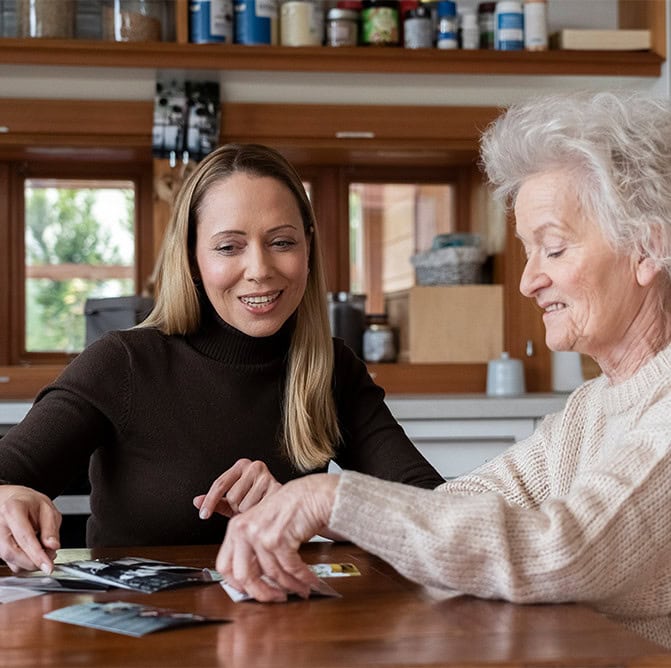 Pflegekraft sieht sich mit Seniorin Fotos an
