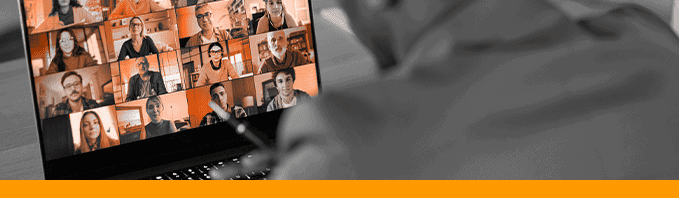 A black and white image of a mam using a laptop, people are on the screen and are all orange