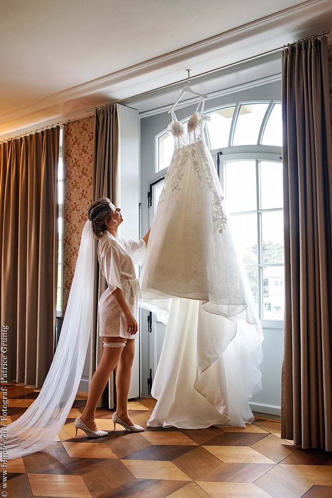Getting Ready Fotoshooting
Die Hochzeitsbraut schaut Ihr Kleid, das am Fenster hängt an. Urheber Hochzeitsfotograf Patrice Grünig