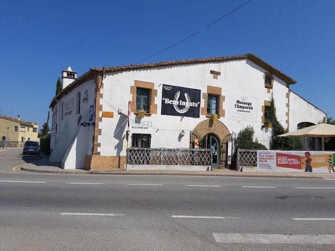 Roasted barn restaurant on a sunny day in Móscara Esporanda, Can Camades, highlighting traditional Spanish architecture and local dining experience in a charming rural setting.