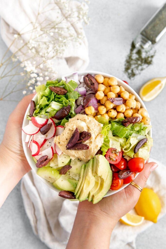 Hands holding up the perfect lunch - a Mediterranean buddha bowl.