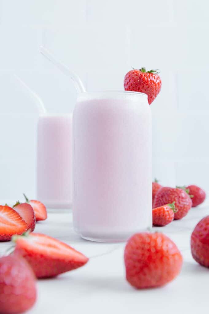 A strawberry smoothie with a glass straw.
