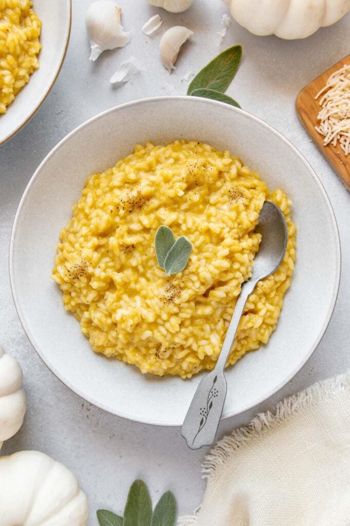 Pumpkin risotto in a serving bowl with a spoon.