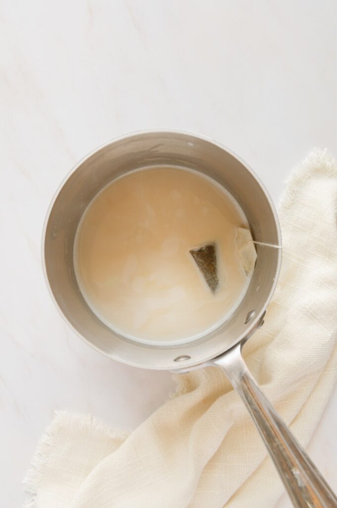chai tea bag steeping in a saucepan of warm milk.