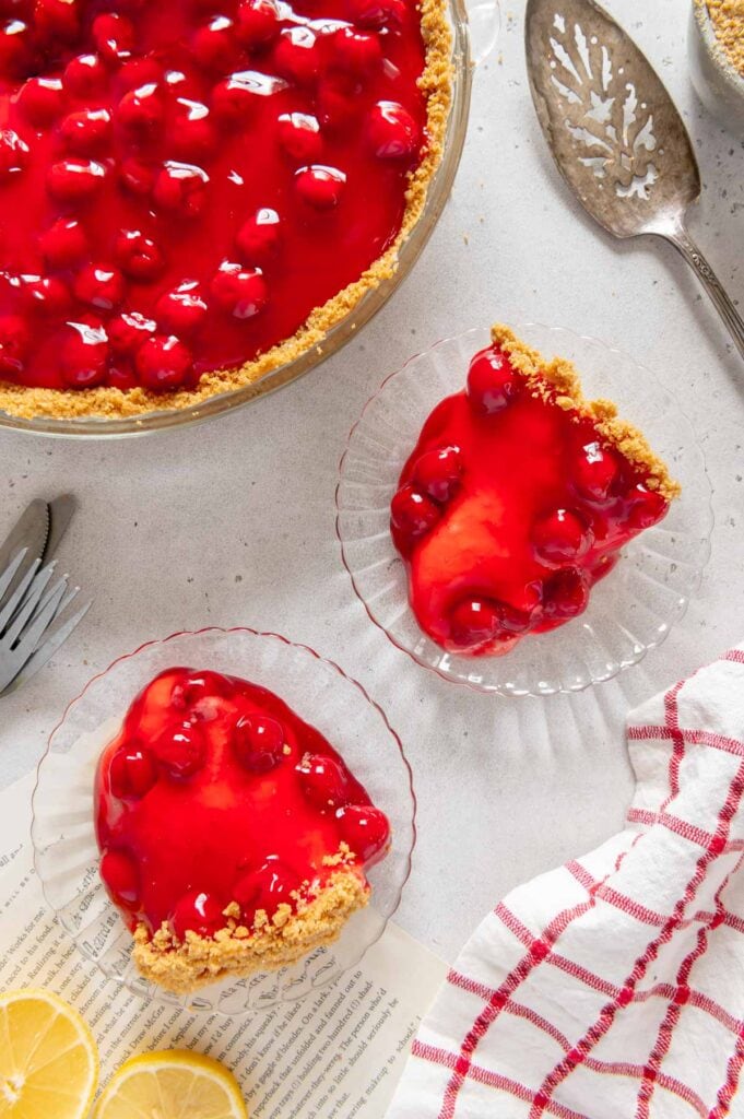 Two sliced of cherry cheesecake on glass plates.