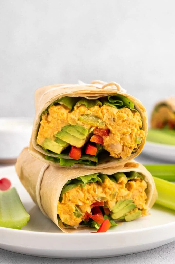 Buffalo Chickpea Wrap cut in half stacked on top of each other on a plate.
