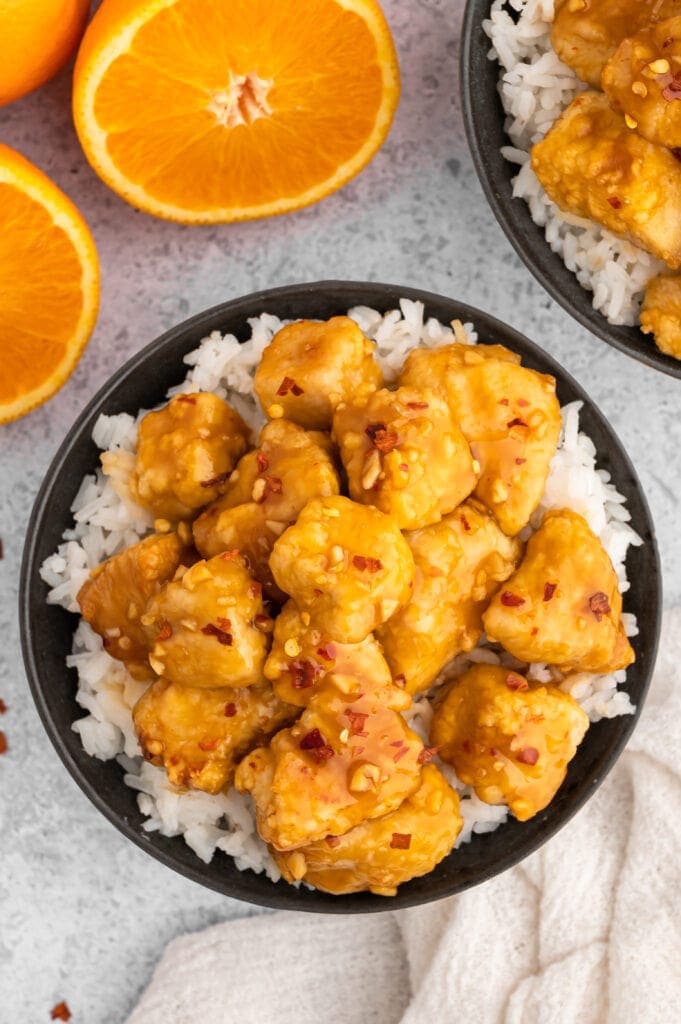 air fryer orange chicken in a black bowl with rice next to an orange