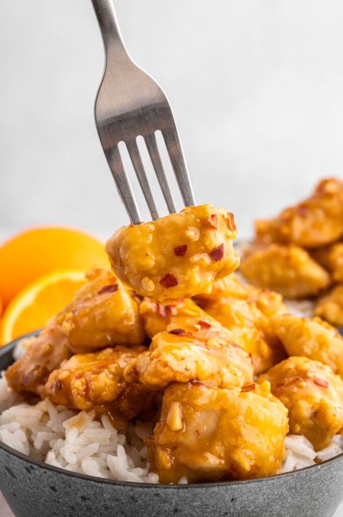 sticking a fork into a piece of air fried orange chicken