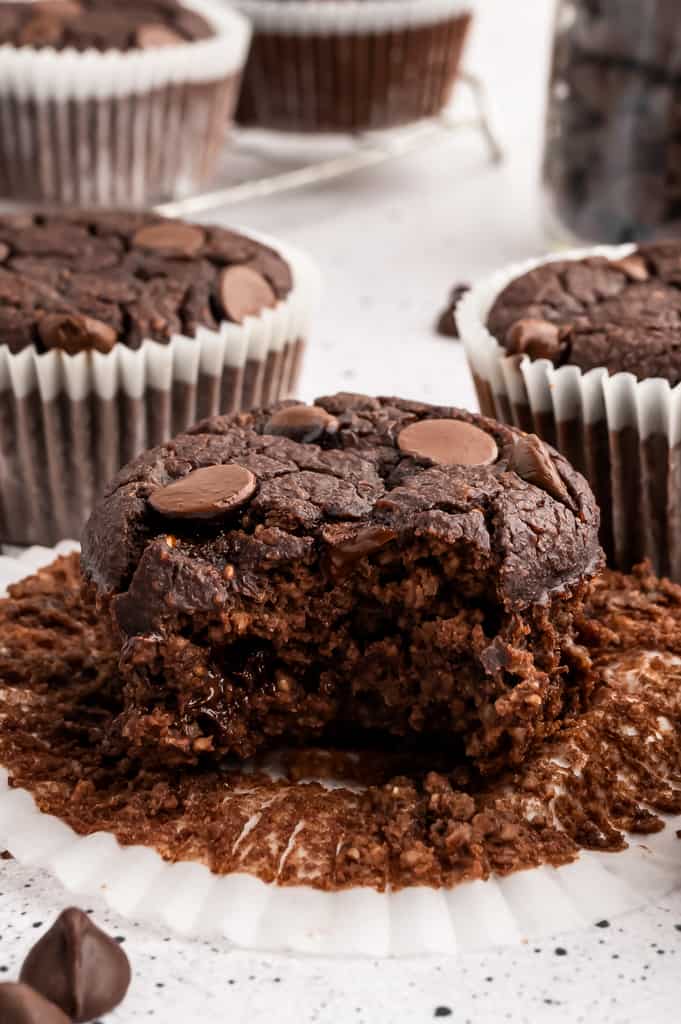 A chocolate protein muffin with a bite taken out.