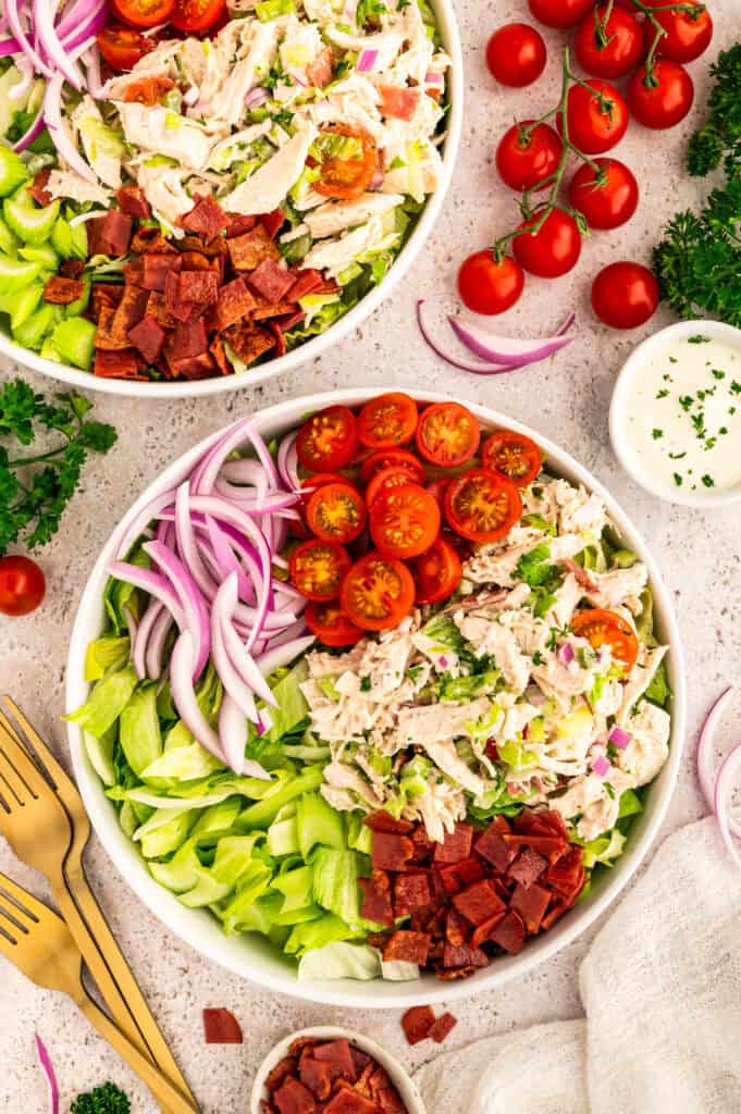 Two bowls of healthy BLT chicken salad next to tomatoes.