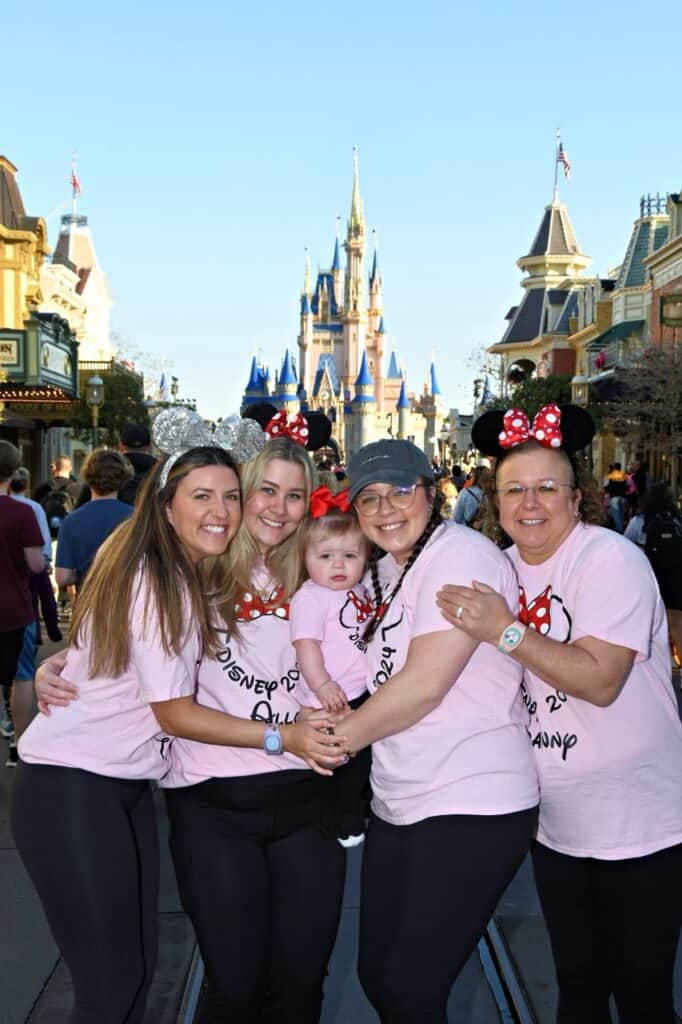 Family wearing Minnie Mouse ears at Disney theme park, smiling in front of Cinderella Castle.