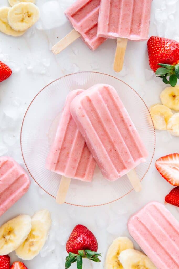 Two popsicles on a pink glass plate.