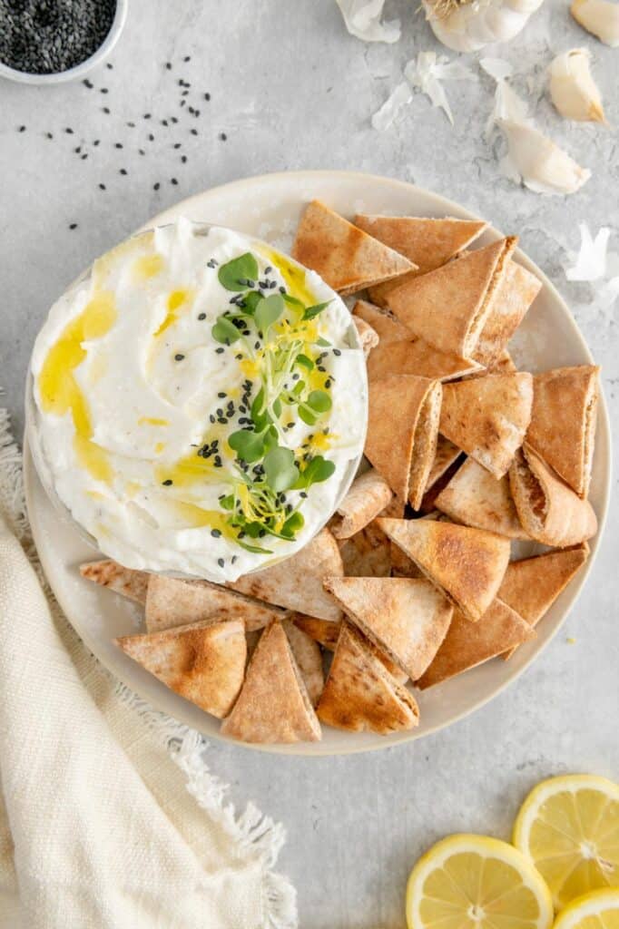 A vegan appetizer for whipped feta tip garnished with microgreens and sesame seeds.
