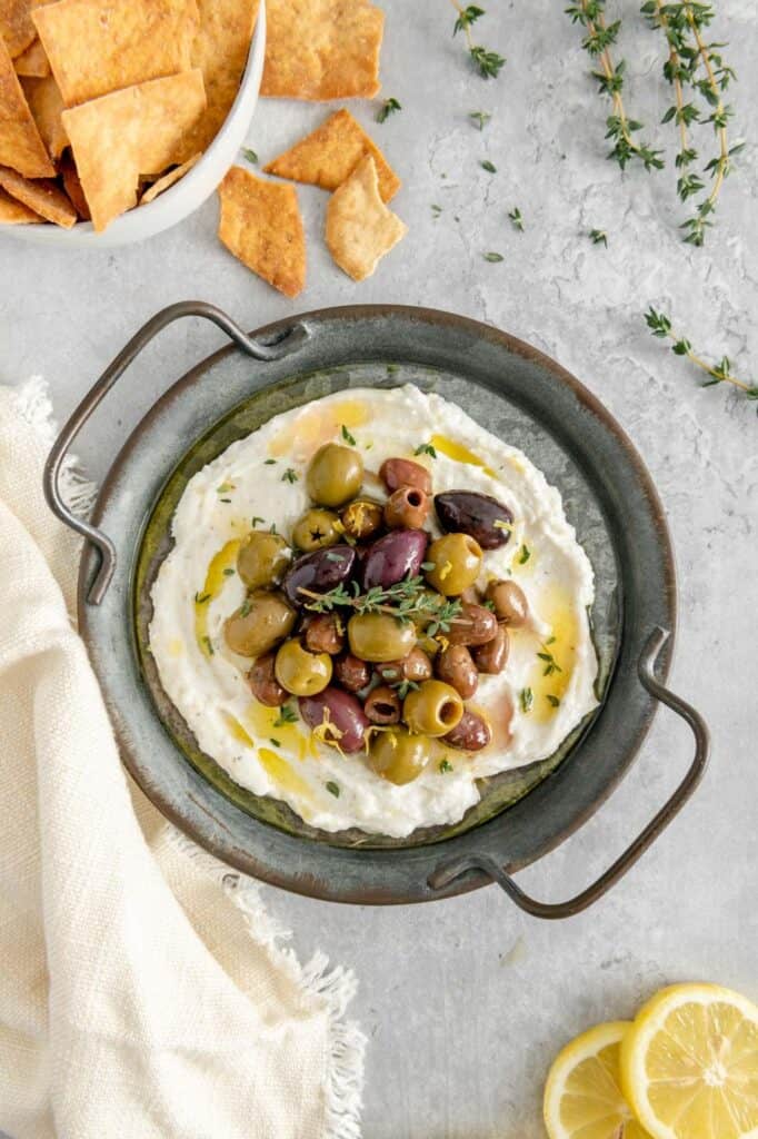 A vegan whipped feta dip on a serving tray with pita chips.