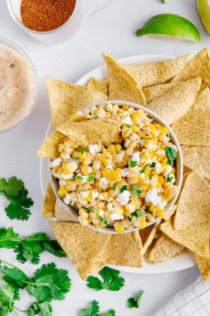 Vegan elote in a serving bowl with chips for dipping.