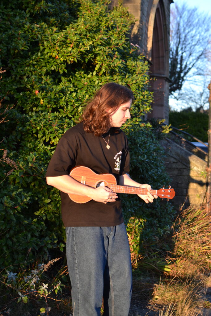 Adam is playing ukulele at the floor