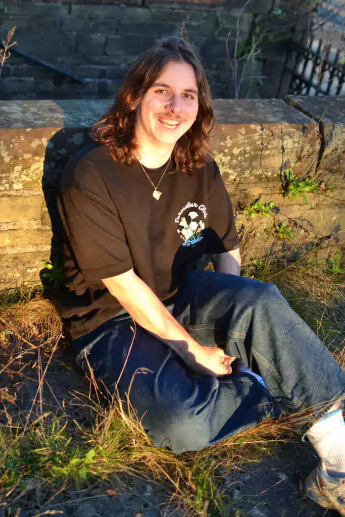 Adam Maghout is sitting and smiling in the sun