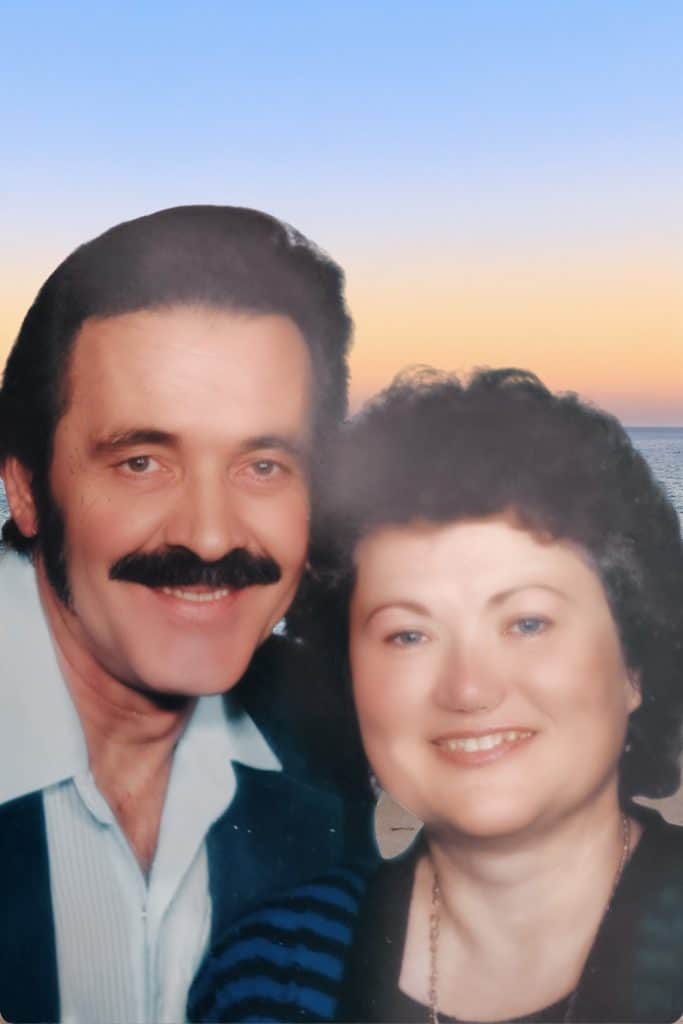 A couple standing together with an ocean sunset behind them, embodying peace, strength, and spiritual presence.