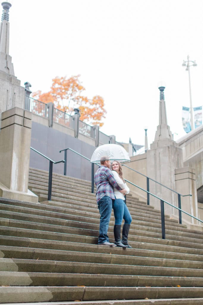Couple posed with umbrella on stairs downtown Ottawa - Rainy Day Engagement Session Downtown Ottawa - Photo Locations Grey Loft Studio - Ottawa Wedding Photographer & Videographer