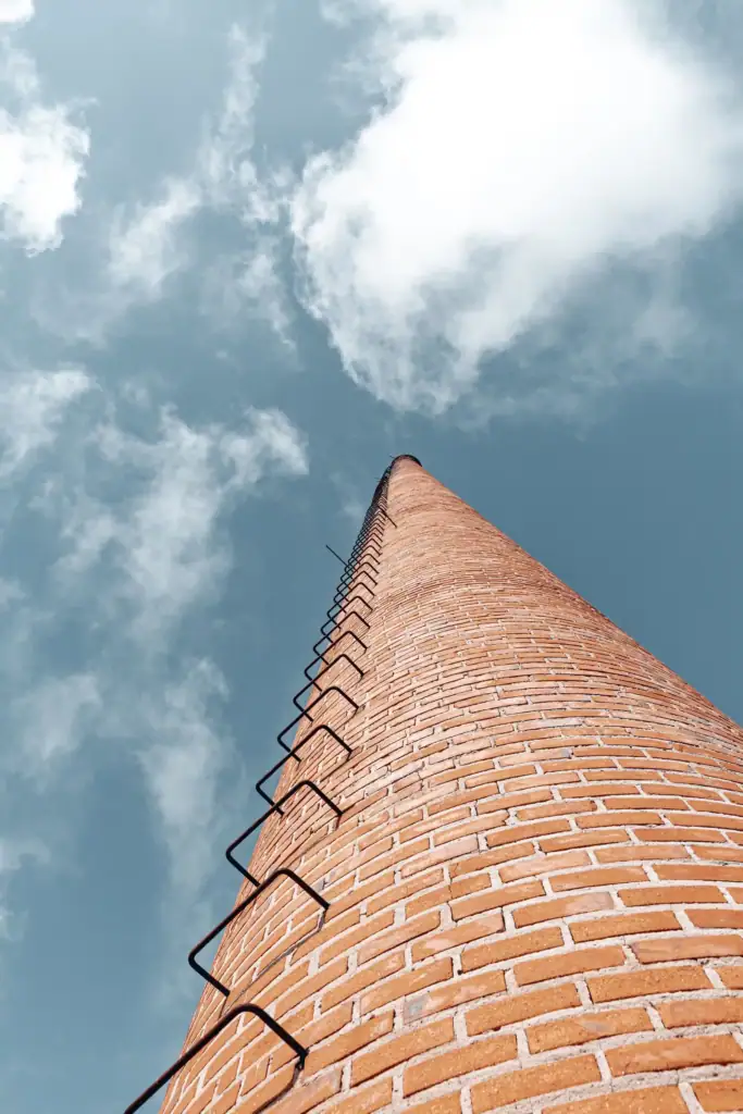 Brick chimney with a ladder against a cloudy sky, symbolising career progression
