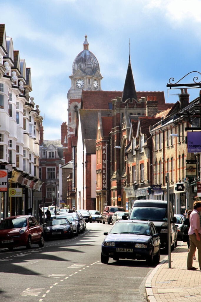 Historische Straßenansicht einer englischen Stadt mit beeindruckender Architektur, Geschäften und einer markanten Uhrturm-Kuppel.