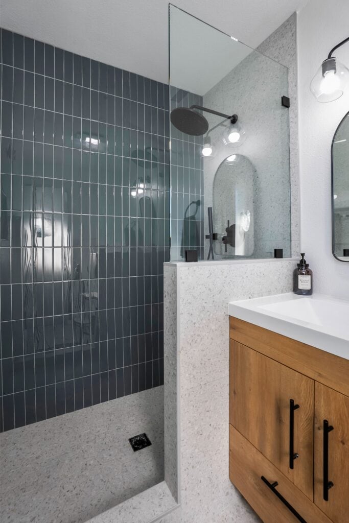 Glass-partitioned shower at 2170 Montclair St North Park with vertical teal subway tile and designer hardware.