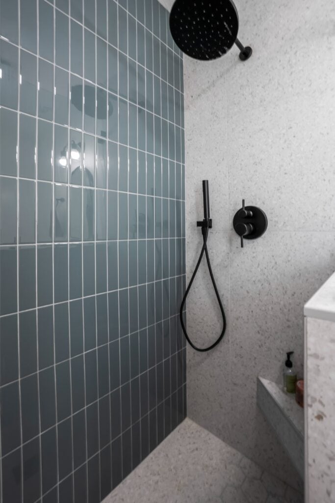 Close-up of matte black rainfall shower head and vertical tile in the newly remodeled bathroom at 2170 Montclair St.