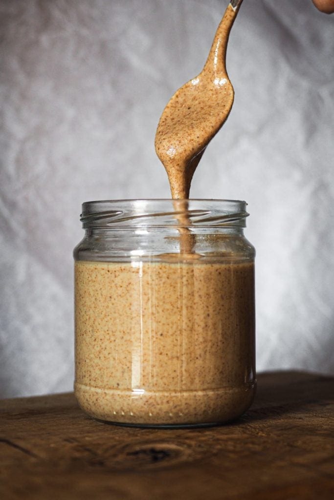 Paula's Apron Homemade Almond Butter How to make Homemade Almond Butter couldn't be easier, healthier and cheaper! Meade with just almonds, it's smooth and creamy. Shot of a jar with almond butter and a spoon pouring almond butter in it. It can be seen how creamy and runny it is.