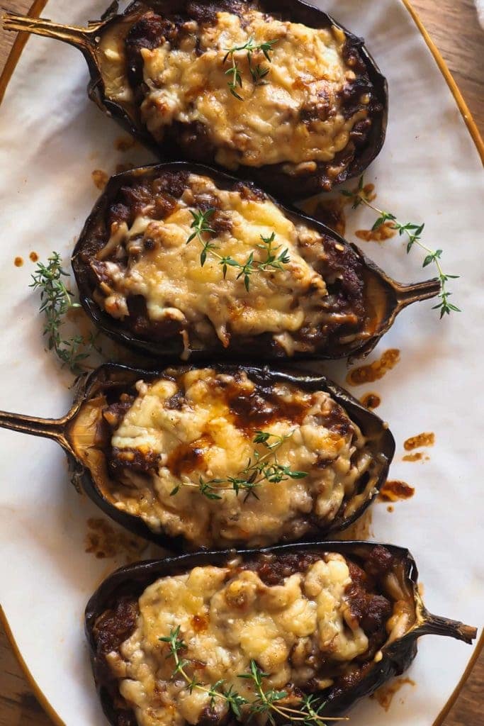 Paula's Apron Sausage Stuffed Aubergine This Sausage Stuffed Aubergine recipe makes a delicious, hearty and wholesome main that everybody will love (no aubergine fans included)! Roasted aubergine is combined with a heavenly tomato sauce, made even better with the addition of sausage and topped with mature cheddar cheese. Overhead close shot of the aubergine served on a white plate and garnished with thyme.