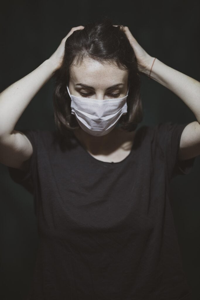 Healthcare professional wearing a mask, experiencing stress and burnout, highlighting the emotional toll faced by healthcare workers in demanding environments.
