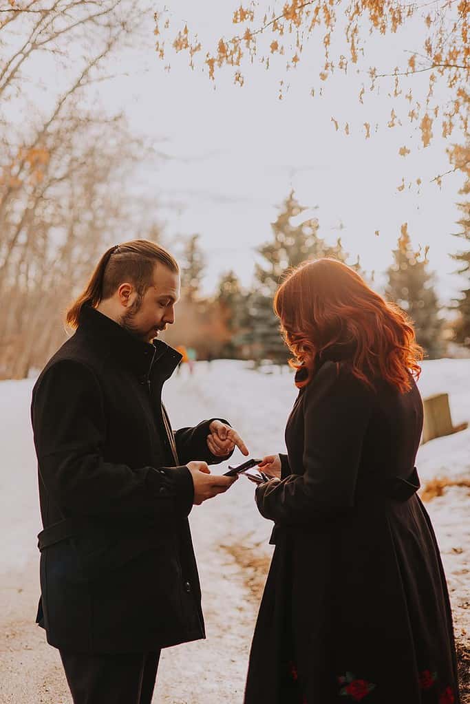 A newly engaged couple looking at their phones and playing Pokemon Go. They are excitedly talking to each other