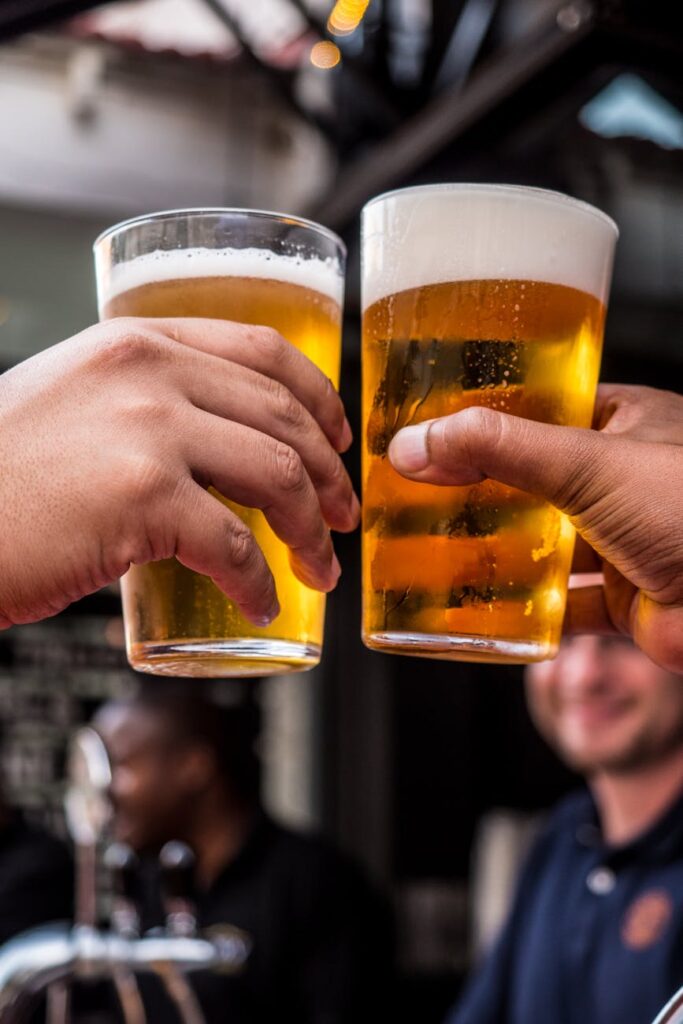 two persons holding drinking glasses filled with beer. German wheat beers