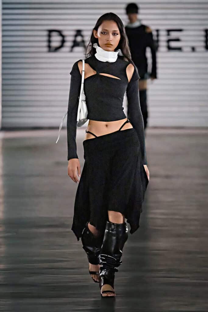 Model in asymmetrical black cut-out outfit from Daphne.lab × Marrknull’s genderless “In a Hurry” runway.
