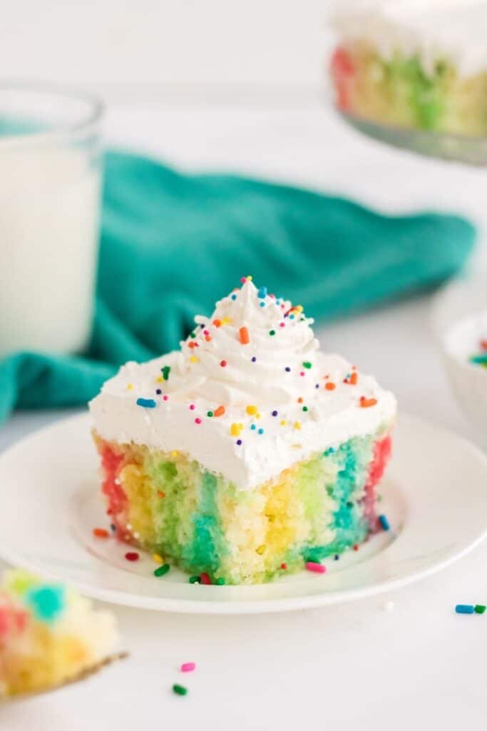 Make a colorful, moist, and utterly delicious cake within minutes with this Rainbow Poke Cake recipe. It is full of flavor and plenty of fun colors, including shades of pink, blue, and yellow!