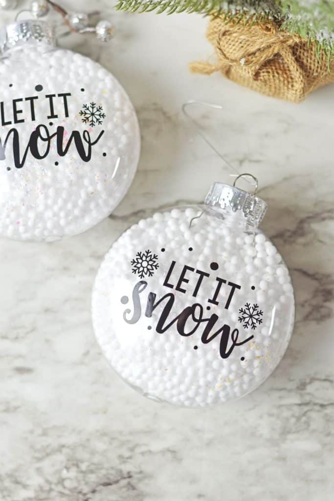 Who says you need the most expensive ornaments to make your Christmas tree look amazing? Learn how to easily create the most beautiful Let It Snow Ornament to hang on the tree or give as a gift. This DIY Ornament is an easy holiday Cricut Craft Idea. It is a great homemade Christmas gift craft idea.