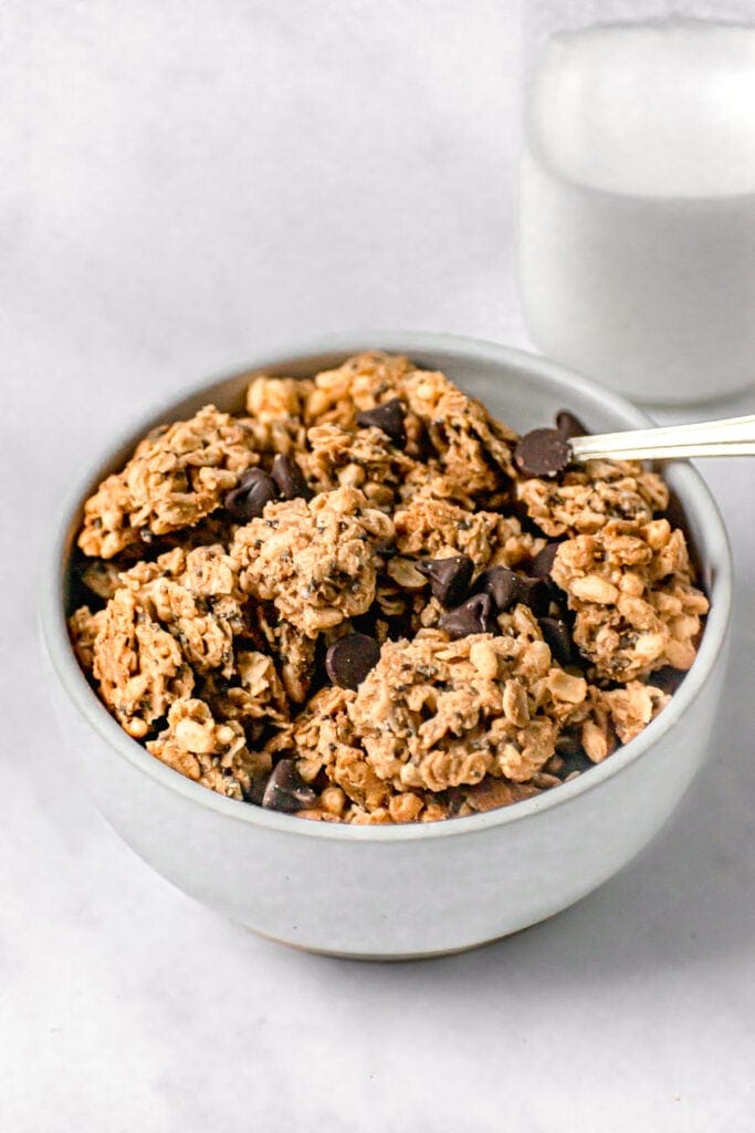 chocolate peanut butter granola in a white bowl next to milk