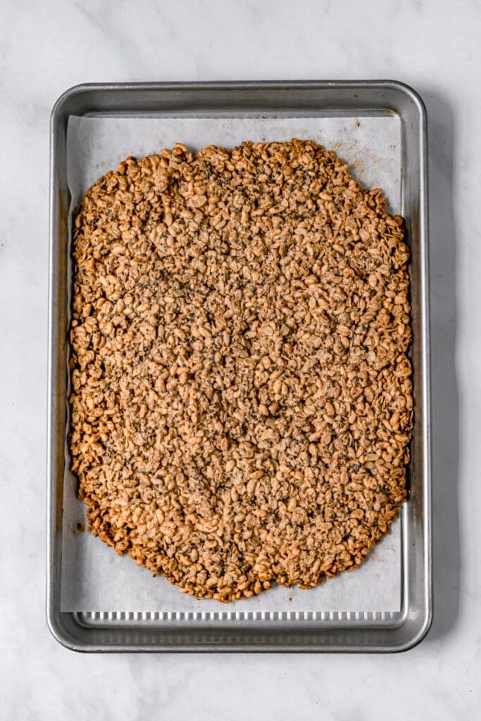 chocolate peanut butter granola on baking sheet before breaking apart
