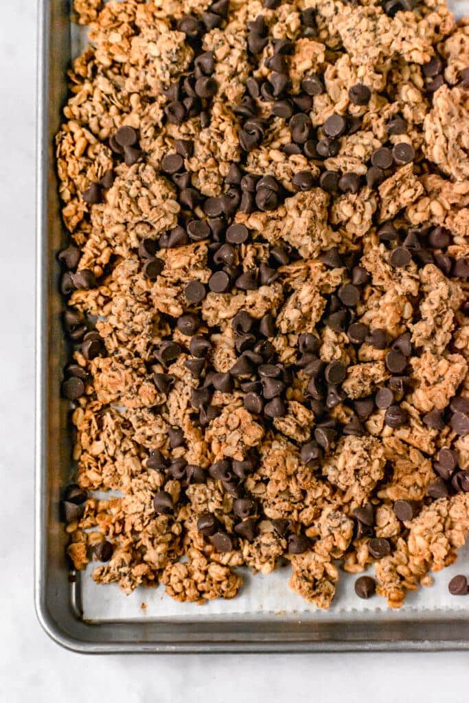 granola on a baking pan with chocolate chips sprinkled on top