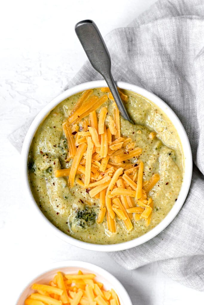 instant pot cheddar broccoli soup in a white bowl with spoon