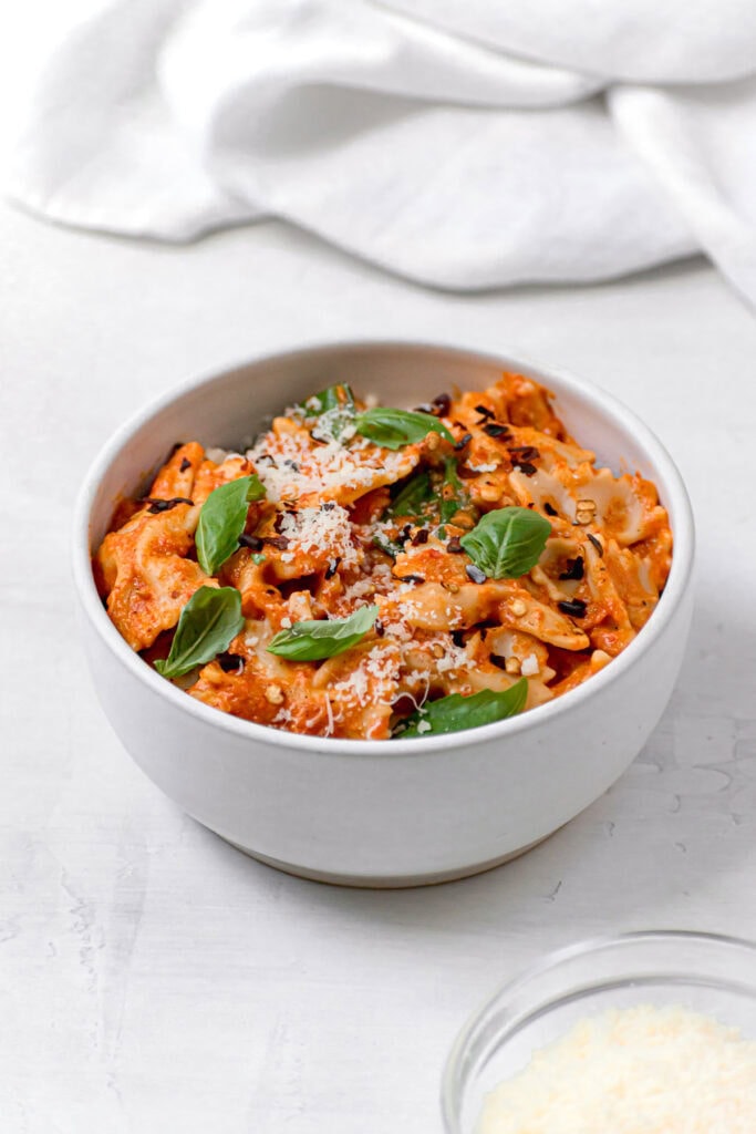 side view of red pepper pasta in a white bowl