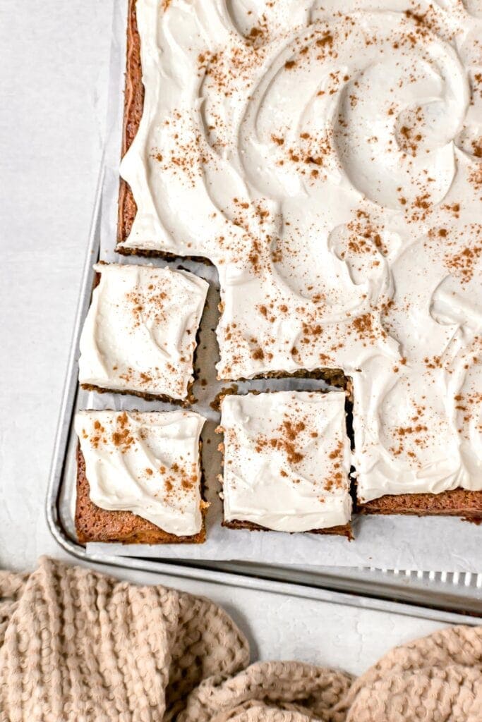 gluten free banana cake with icing in the baking sheet with three squares cut