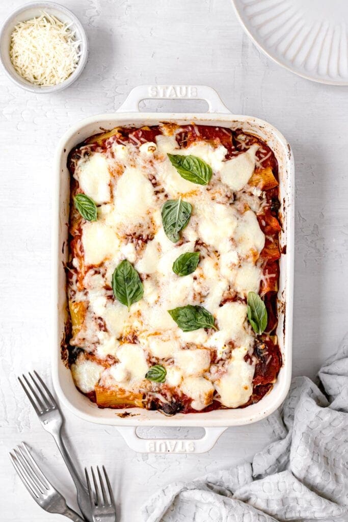 fresh baked vegetarian ziti next to cheese and forks