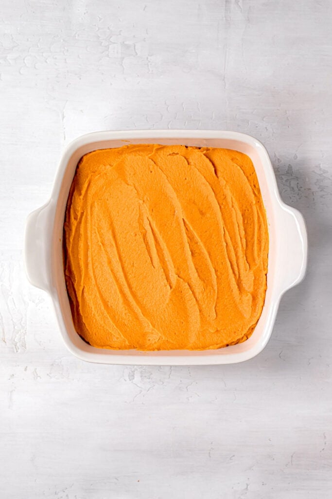 close up of sweet potatoes evenly spread throughout a white baking dish
