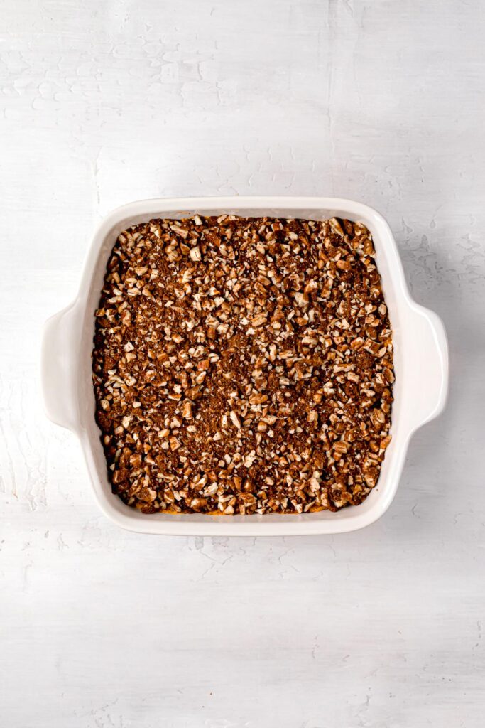 close up of pecans spread on top of paleo sweet potato casserole in a white baking dish